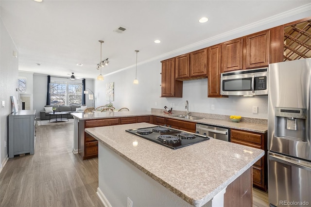 kitchen featuring appliances with stainless steel finishes, ceiling fan, sink, decorative light fixtures, and light hardwood / wood-style floors