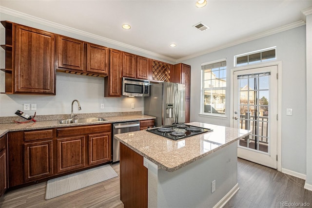 kitchen featuring appliances with stainless steel finishes, crown molding, sink, hardwood / wood-style flooring, and a kitchen island