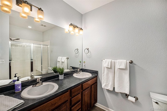 bathroom featuring vanity, toilet, and a shower with shower door