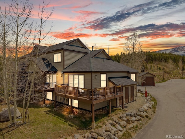10 River Park Dr Unit A, Breckenridge, CO 80424 - back of property at dusk featuring a shingled roof, an outbuilding, a wooden deck, and a detached garage