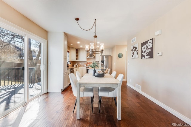 dining room with dark wood-style floors, baseboards, visible vents, and a chandelier