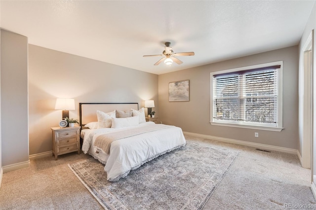 bedroom with visible vents, light colored carpet, baseboards, and ceiling fan