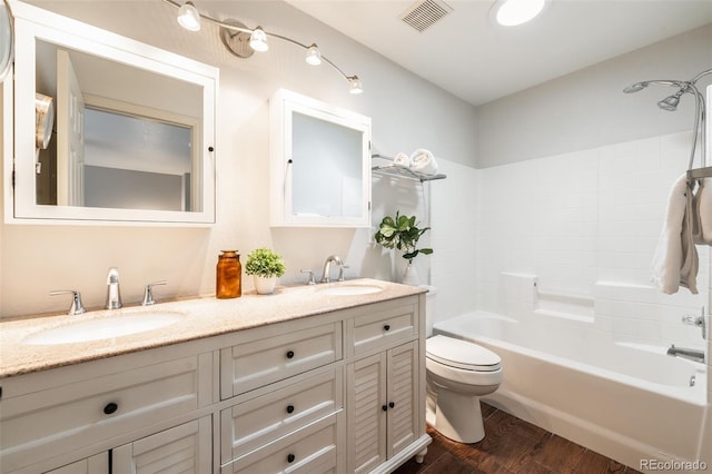 bathroom featuring toilet, wood finished floors, visible vents, and a sink