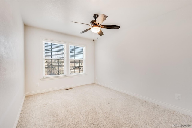 carpeted empty room featuring visible vents, a ceiling fan, and baseboards