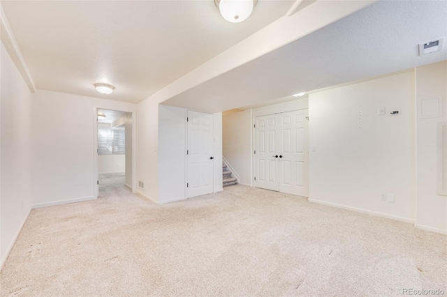 carpeted spare room with stairway, baseboards, and visible vents