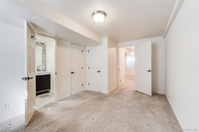 unfurnished bedroom with two closets, baseboards, carpet, and ensuite bath