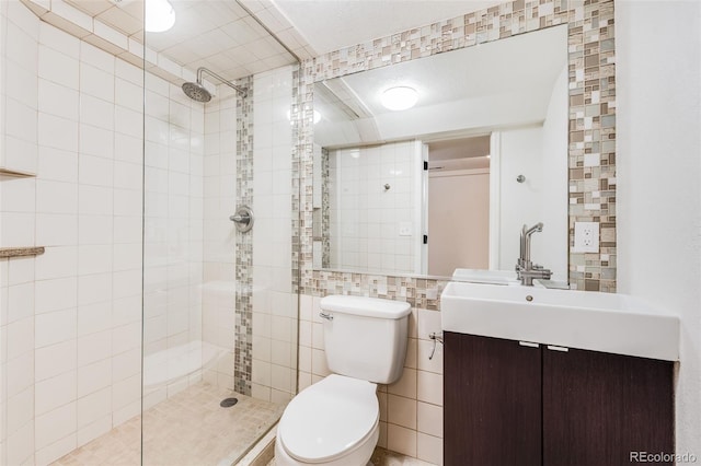 full bath with toilet, tile walls, vanity, and a tile shower