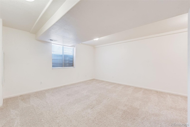 empty room with carpet flooring, a textured ceiling, and baseboards