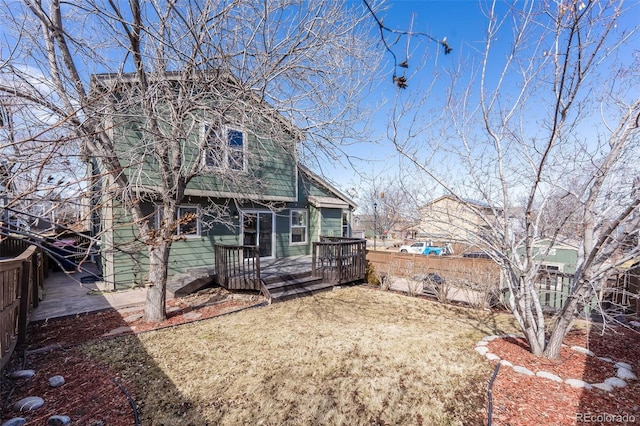 view of front of house featuring a wooden deck, a front yard, and fence