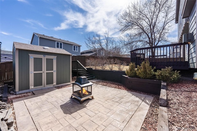 view of patio featuring a wooden deck, a storage unit, a fire pit, and an outdoor structure