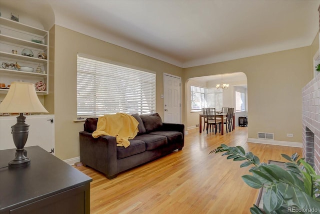 living room featuring a fireplace, wood-type flooring, and a chandelier