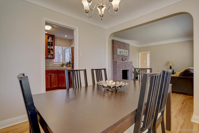 dining space featuring a fireplace, a chandelier, and light hardwood / wood-style floors