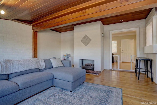 living room featuring wood ceiling, a fireplace, light hardwood / wood-style floors, and brick wall