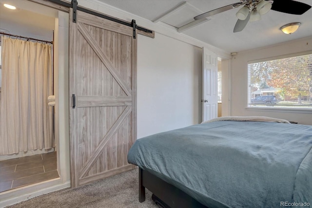 carpeted bedroom with ceiling fan and a barn door