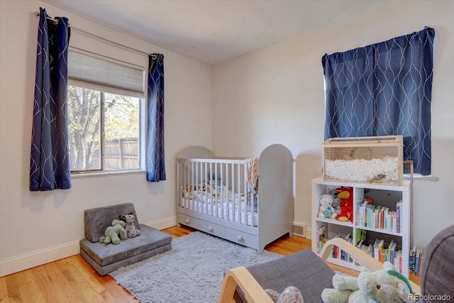 bedroom featuring hardwood / wood-style floors and a nursery area