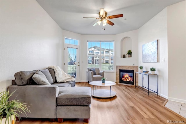 living room featuring a tile fireplace, light hardwood / wood-style flooring, and ceiling fan