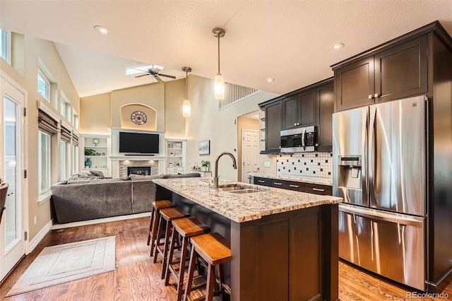 455 Bexley St, Littleton, CO 80126 - kitchen featuring stainless steel appliances, ceiling fan, light wood finished floors, light stone countertops, and a fireplace