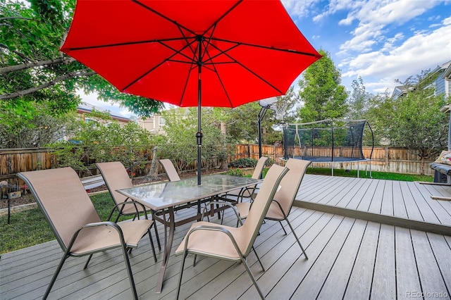 455 Bexley St, Littleton, CO 80126 - wooden deck featuring a trampoline, outdoor dining space, and a fenced backyard