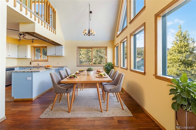 dining room featuring a chandelier, high vaulted ceiling, dark wood-type flooring, and sink