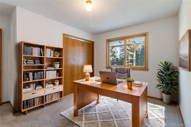 carpeted home office featuring a textured ceiling