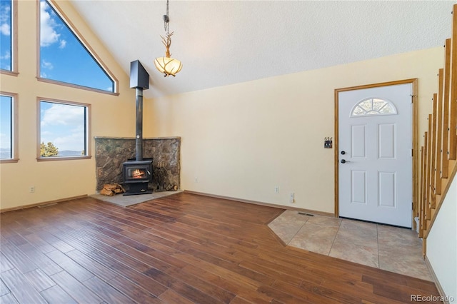 entrance foyer with wood-type flooring, a wood stove, and a wealth of natural light