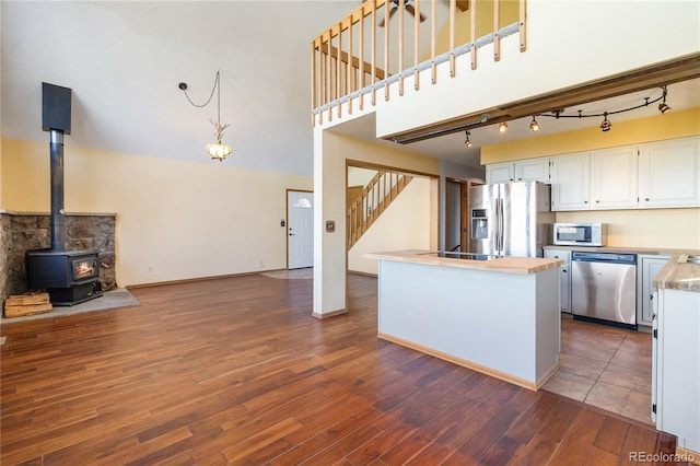 kitchen with white cabinets, dark hardwood / wood-style floors, a wood stove, and appliances with stainless steel finishes