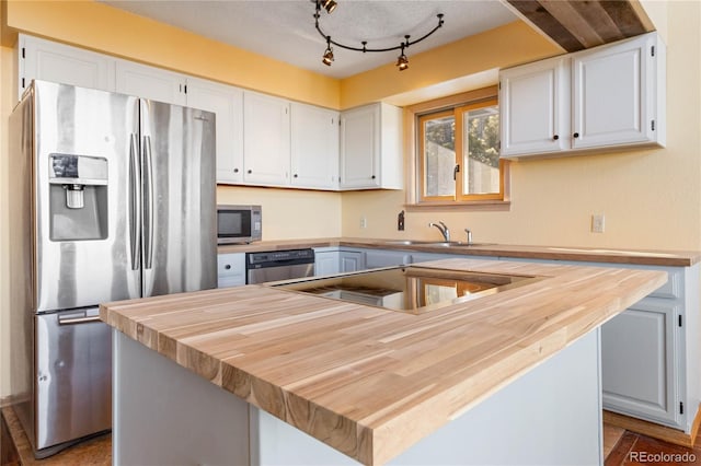 kitchen with sink, white cabinets, stainless steel appliances, and a kitchen island