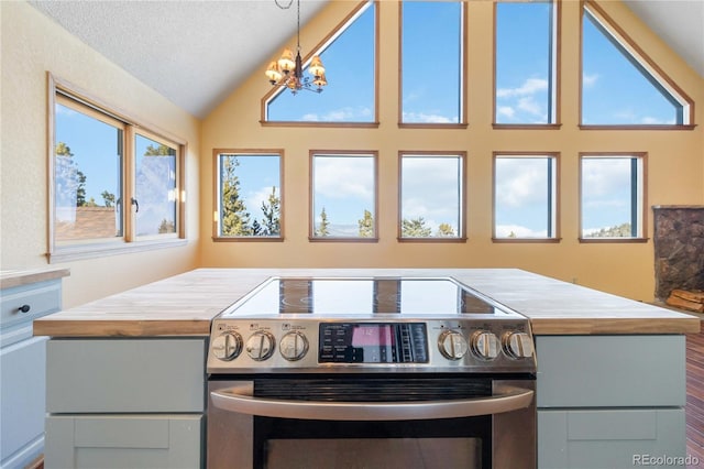 kitchen with electric range, a notable chandelier, a textured ceiling, vaulted ceiling, and decorative light fixtures