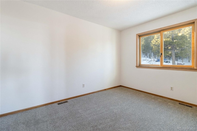 carpeted empty room featuring a textured ceiling