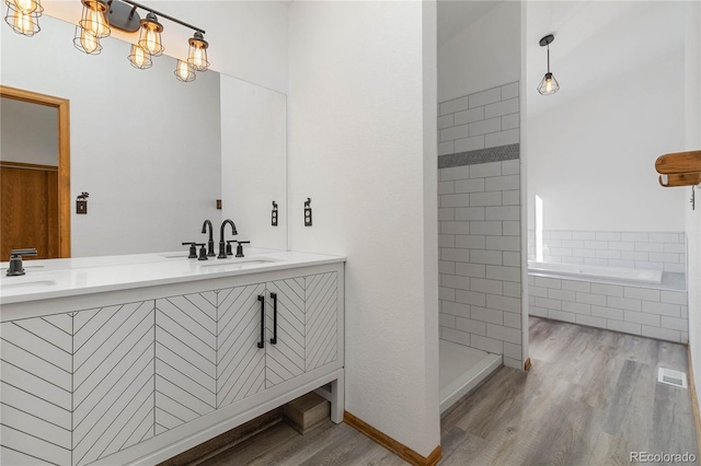 bathroom with plus walk in shower, wood-type flooring, and vanity