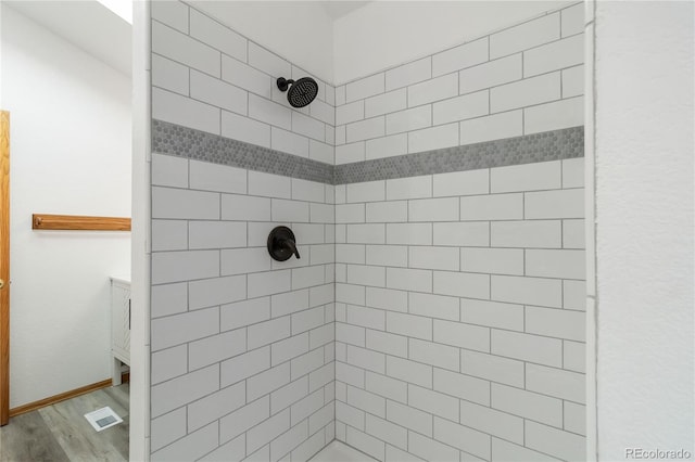 bathroom featuring hardwood / wood-style floors and a tile shower