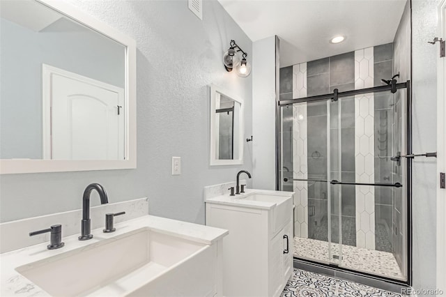 16321 Clayton St, Thornton, CO 80602 - full bathroom with a shower stall, a textured wall, two vanities, and recessed lighting