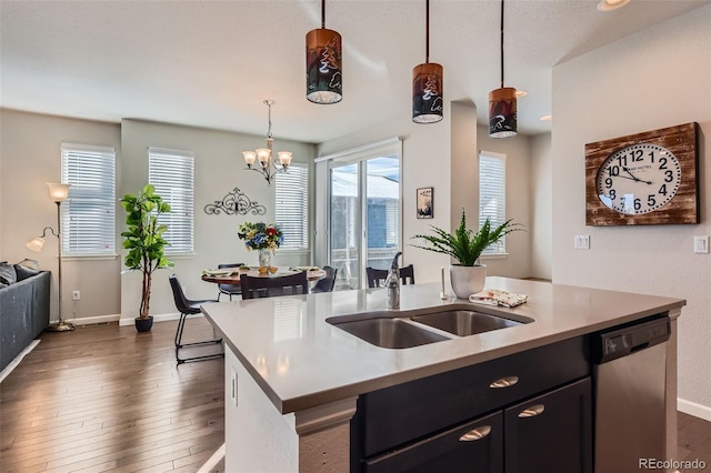 kitchen with dark wood-type flooring, sink, stainless steel dishwasher, an island with sink, and pendant lighting