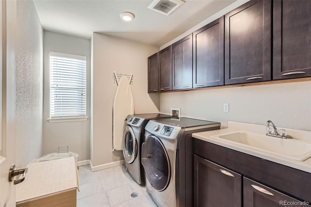 laundry area with cabinets, light tile patterned flooring, sink, and washer and clothes dryer