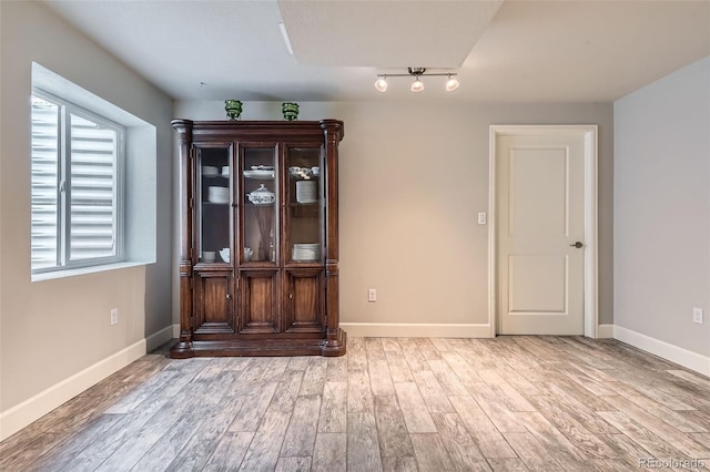 empty room with light hardwood / wood-style floors and rail lighting