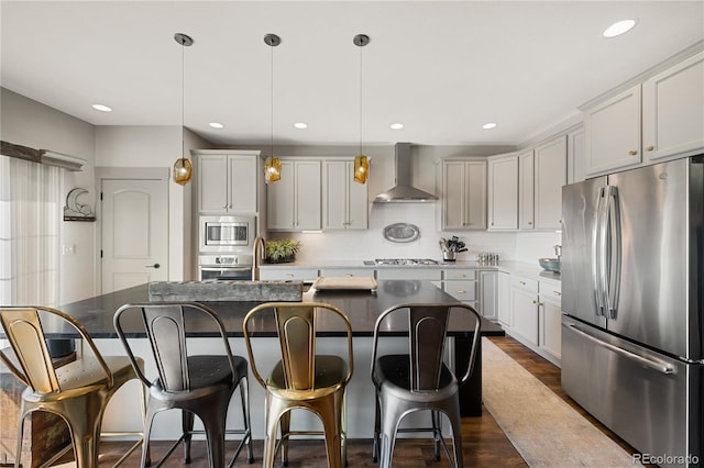 8872 E 47th Ave, Denver, CO 80238 - kitchen featuring appliances with stainless steel finishes, wall chimney exhaust hood, backsplash, dark wood-style flooring, and a breakfast bar area