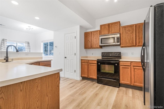 kitchen featuring sink, light hardwood / wood-style floors, kitchen peninsula, and appliances with stainless steel finishes