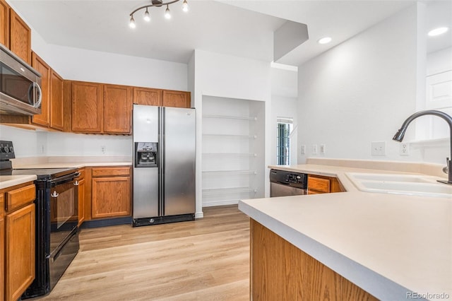 kitchen featuring appliances with stainless steel finishes, sink, light wood-type flooring, and kitchen peninsula