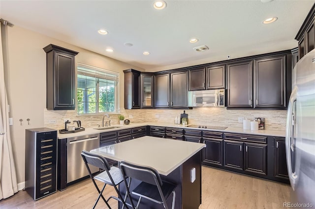 kitchen featuring appliances with stainless steel finishes, a sink, backsplash, recessed lighting, and light wood-type flooring