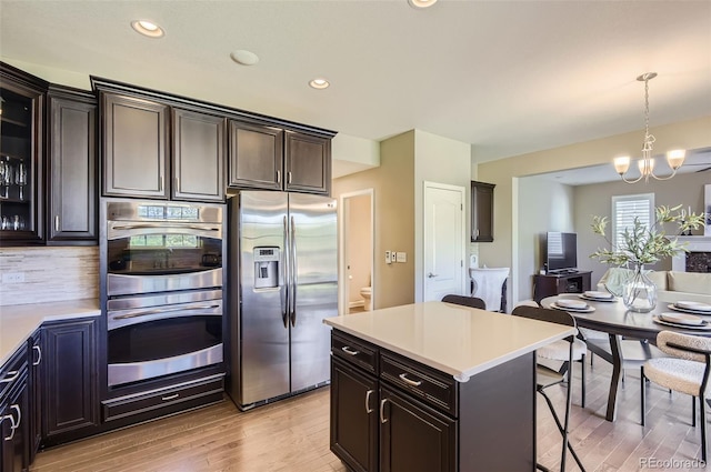 kitchen with stainless steel appliances, a kitchen breakfast bar, light wood finished floors, light countertops, and recessed lighting