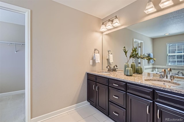 bathroom with double vanity, baseboards, and tile patterned floors