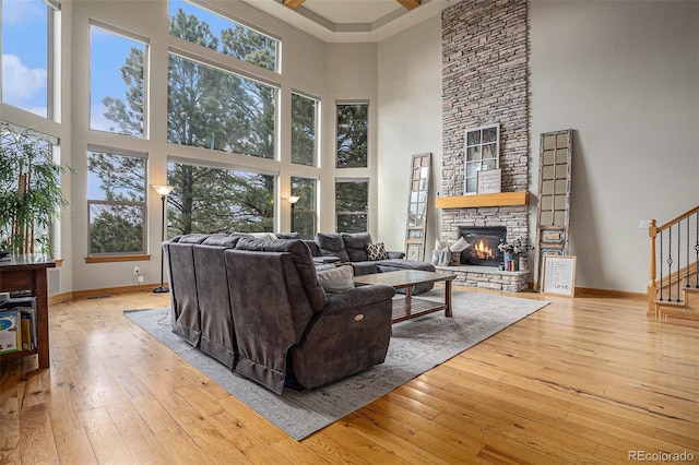 12161 S Leaning Pine Ct, Parker, CO 80134 - living area with wood-type flooring, stairs, a towering ceiling, a stone fireplace, and baseboards