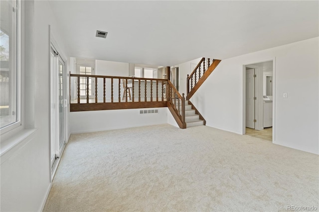 carpeted empty room featuring stairs and visible vents