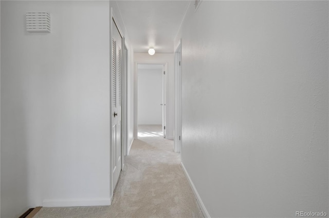 hall featuring light colored carpet and baseboards