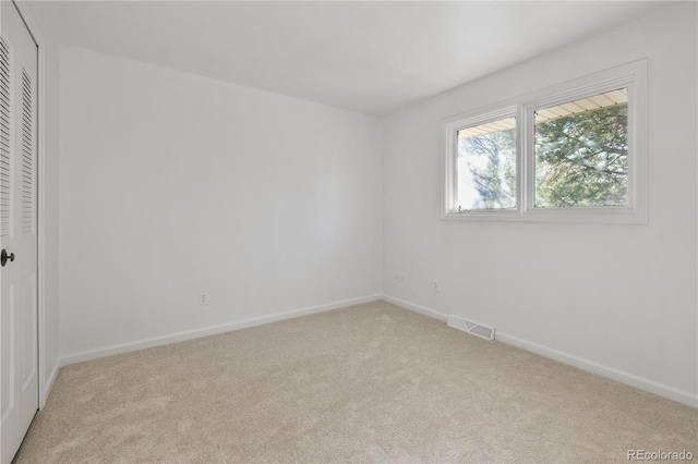 unfurnished bedroom featuring light colored carpet, visible vents, a closet, and baseboards