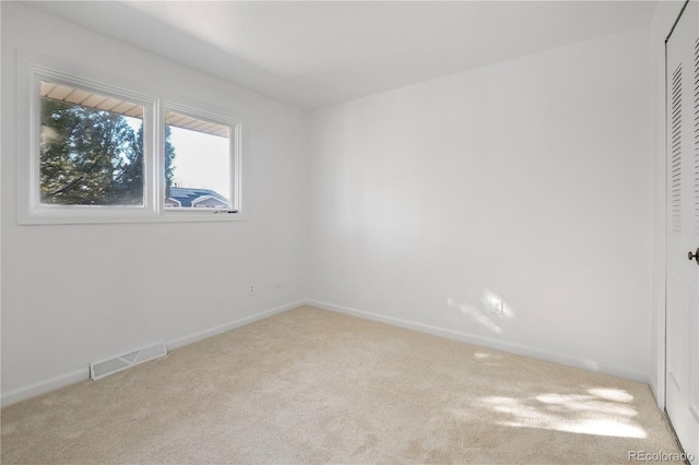 carpeted spare room featuring baseboards and visible vents
