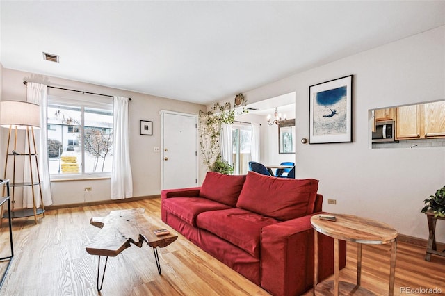 living room featuring a chandelier and light wood-type flooring