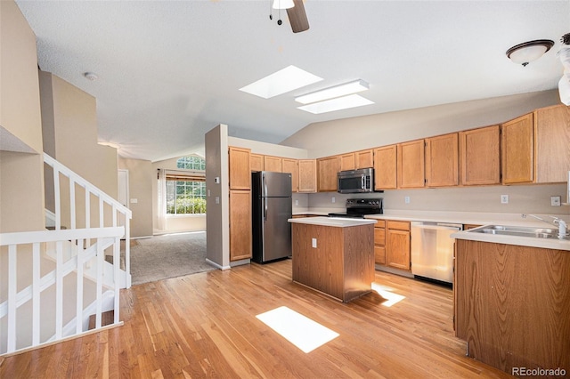 9651 Lameria Dr, Highlands Ranch, CO 80130 - kitchen with stainless steel appliances, a kitchen island, light wood-style flooring, vaulted ceiling, and light countertops
