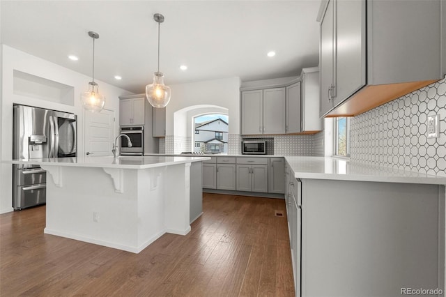 kitchen with appliances with stainless steel finishes, dark hardwood / wood-style floors, gray cabinets, and a wealth of natural light