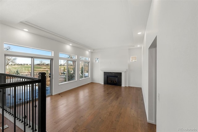 unfurnished living room featuring a healthy amount of sunlight, wood-type flooring, and a tiled fireplace